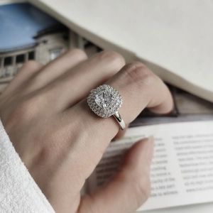Close-up of cushion cut halo ring in 925 sterling silver worn on a finger