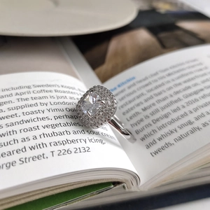 Macro shot of silver ring with double halo square zircon placed between book pages