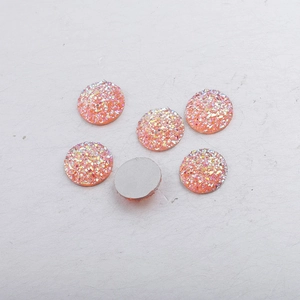Macro detail of 14mm round flatback resin cabochons with sparkling orange glitter texture