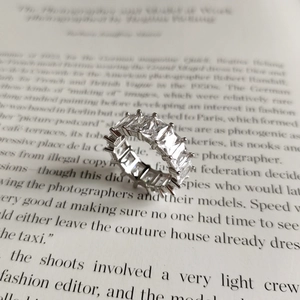 Macro shot of 925 sterling silver eternity ring with emerald cut stones on a book