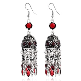 Close-up of vintage silver floral earrings with red gemstones and tassel charms