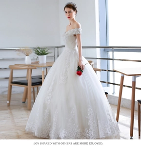 Detail of elegant off-the-shoulder lace neckline and floral embroidery on a white wedding gown
