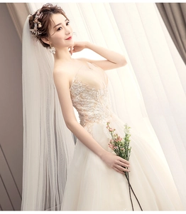 Close-up of strapless wedding dress featuring intricate lace, shiny crystals and floral hair clip