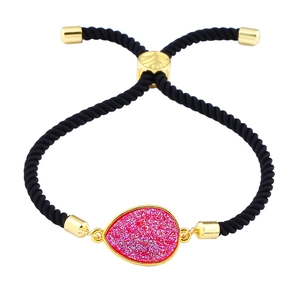 Detail eines rosa Druzy-Steins am schwarzen Webarmband mit verstellbarem goldfarbenem Verschluss