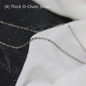 Macro shot of silver-colored thick O-chain necklace on a textured stone background