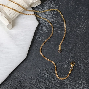 Detailed close-up of gold titanium twist chain necklace with lobster clasp closure