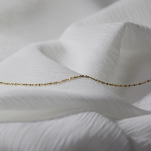 Detailed view of elegant gold plated stainless steel snake chain on white fabric