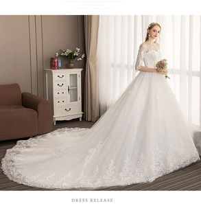 Detail of elegant white lace wedding dress featuring long train and off-shoulder sleeves