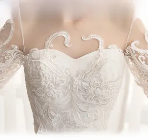 Close-up of off-shoulder wedding dress with intricate floral lace and satin details