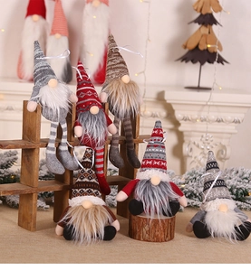 Close-up of assorted plush Christmas gnomes with knit hats on a rustic wooden shelf