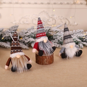 Three Christmas gnome ornaments with knitted hats and long beards on a festive fireplace