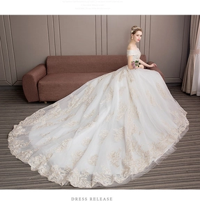 Close-up of luxury off-shoulder wedding gown with gold lace embroidery and long train