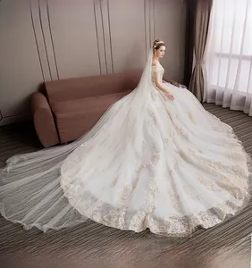 Detail of off-shoulder wedding gown featuring gold embroidery and long luxury train