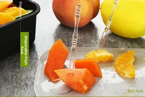 Macro detail of transparent plastic fruit fork with non-slip handle on fresh papaya