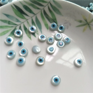 Close-up of natural mother of pearl evil eye loose beads on a white ceramic tray