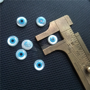 Measuring a natural white mop evil eye shell bead with a brass vernier caliper tool