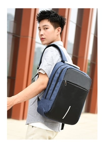 Detail of blue denim and black leather laptop backpack with reflective strip and USB port