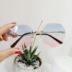 Detail of rimless polygon sunglasses with blue-pink gradient lenses and gold metal temples