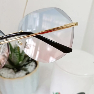 Detail of rimless gradient blue-pink lens and slim gold metal temples on sunglasses