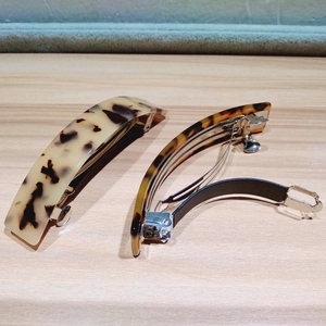Close-up of tortoise shell pattern hair clips with metal spring mechanism on wood