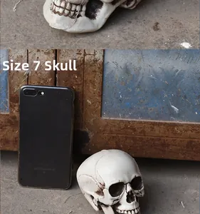 Detailed size comparison of realistic skull prop next to a smartphone for scale
