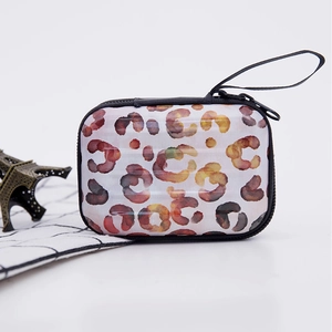 Mini suitcase coin purse with watercolor leopard print and black wrist strap on desk