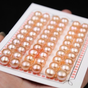 Close-up of high-luster pink freshwater button pearls displayed on a white card mount