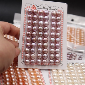 Detailed view of multiple pairs of natural purple freshwater pearl stud earrings on a card