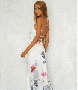 Detail of cross-back straps and floral print on white maxi dress with side slit