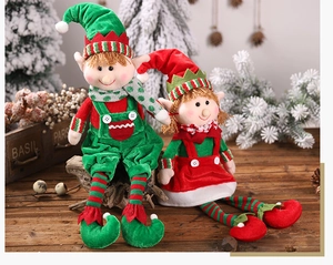 Pair of plush Christmas elf dolls in red and green sitting on a rustic wooden table