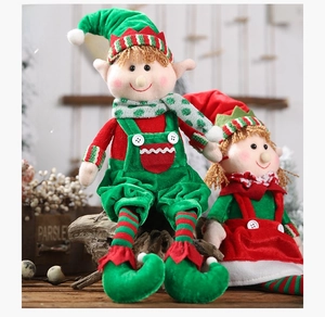 Detail of Christmas elf plush dolls in red and green outfits sitting on natural wood