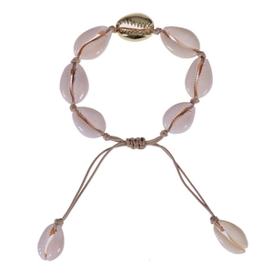 Detail of adjustable cowrie shell bracelet with a central gold-tone shell on beige cord