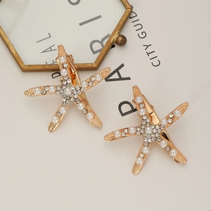 Lot de 2 barrettes étoile de mer dorées avec perles et strass sur fond de décor élégant