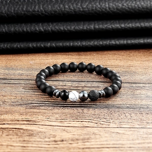 Detail of matte black onyx beads with white turquoise and volcanic stone on wood