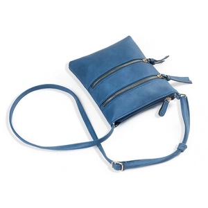Detail view of the multi-zipper blue crossbody bag with three pockets and adjustable strap