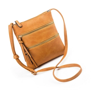 Close-up of litchi texture brown crossbody bag with triple zipper pockets and tassels