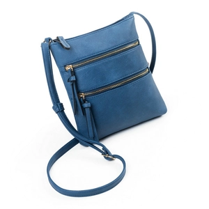 Detailed view of dark blue crossbody bag with three functional gold zippers and pebble leather