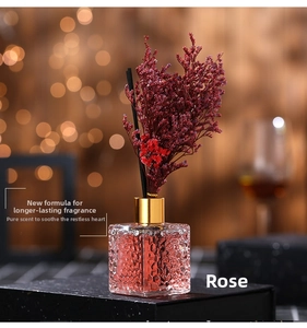 Detail of pink hammered glass diffuser bottle with dried roses and black fiber reeds
