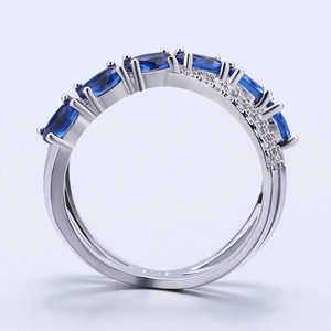 Detailed close-up of a silver X-shaped copper ring featuring blue and white zircons