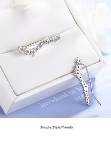 Macro shot of silver star ear climbers with sparkling zircon stones on a jewelry box