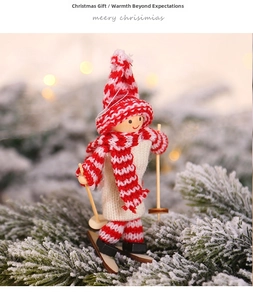 Close-up of a wooden ski doll ornament with red knit hat on snowy pine branches