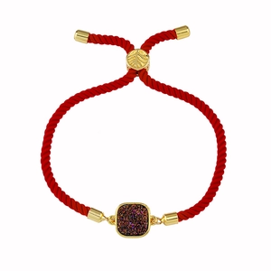 Détail du bracelet en cordon rouge avec cristal violet et curseur doré motif de feuille