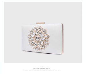 Detail of pearl white satin clutch with crystal flower motif and gold metal frame