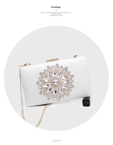 Close-up of elegant white hard shell evening bag with crystal flower and gold chain strap