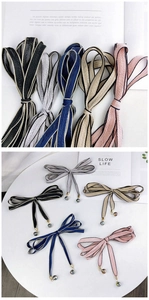 Détail de fines écharpes rubans avec d'élégants pendentifs en métal et perles de cristal