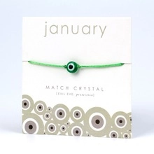 Detail of January crystal green evil eye protective cord bracelet on display card
