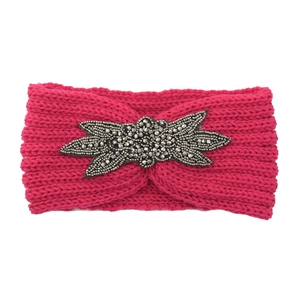 Detail der handgenähten Perlenverzierung auf dem rosaroten Strickstirnband