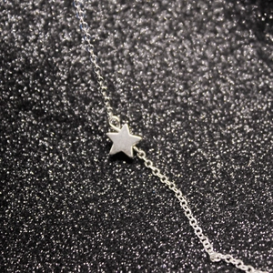 Close-up of a silver pentagram star pendant on a delicate metal chain necklace