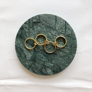 Detail of five interlocking gold plated rings set on a green marble coaster display