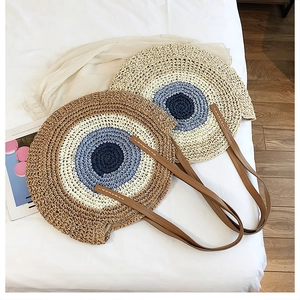 Détail des sacs de plage ronds en paille tressée avec couleurs contrastées et anses cuir